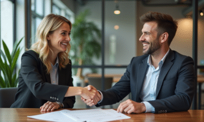 Deux professionnels souriants se serrent la main dans un bureau moderne